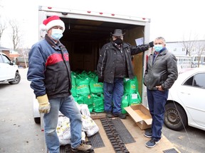 Gerald Dupuis, left, Marcel Prevost and Regent Dupuis pose for a photo amid baskets of food and bags of potatoes to be distributed to families in need at the Jem Mart on Kathleen Street in Sudbury on Saturday, December 18, 2021. Members of Club Richelieu les Patriotes, family members and friends prepared some 125 Christmas baskets, filled with ham, tourtiere, vegetables, fruits, canned goods and other items, continuing a 30-year-old tradition which has seen roughly  3,100 baskets distributed in all. The initative also benefitted from support of Ste-Anne-des-Pins Parrish, which contributed to the production of baskets and made gift cards available for children. Ben Leeson/The Sudbury Star/Postmedia Network