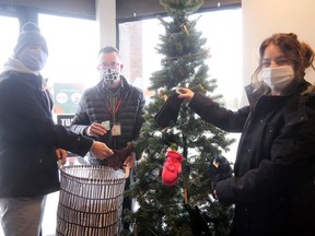 Shawn Crane, media sales consultant from the Norfolk and Tillsonburg News, on the left, Mark Renaud, Tillsonburg BIA executive director, and Karlee Slattery, BIA events and marketing coordinator, gather up this year's Mitten Tree donations. The Downtown Tillsonburg BIA Christmas Crawl, which encourages people to shop local, continues until Dec. 23.