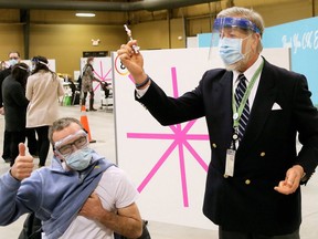 Rick Walker (left) gives a thumbs up after receiving his first dose of COVID-19 vaccine from Chatham-Kent medical officer of health Dr. David Colby at the Chatham-Kent COVID-19 vaccination clinic in February at the John D. Bradley Convention Centre. Walker, the maintenance supervisor at Riverview Gardens long-term care home, was the first health care worker to be vaccinated at the clinic. Mark Malone/Postmedia