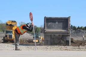 A construction worker stretches out while directing traffic on the Michigan Line as work continues on Sifton's Magnolia Trails subdivision in Sarnia.