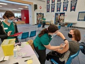 Fourth-semester Loyalist College practical nursing student Emily Paris, centre, injects college employment advisor Lyndsay Kerik with a booster dose of COVID-19 vaccine Dec. 29 at the college. At left is third-semester practical nursing student Hannah McCrory.