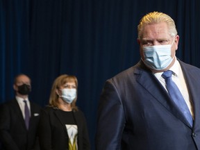 Ontario Premier Doug Ford, right, alongside Health Minister Christine Elliot and Finance Minister Peter Bethlenfalvy, attend a news conference in Toronto on Monday, during which it was announced Ontario is moving schools online and pausing non-urgent surgeries as part of its bid to slow the spread of COVID-19 as the Omicron variant drives infections to record levels and threatens hospital capacity. THE CANADIAN PRESS/Chris Young