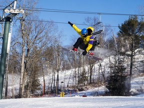 Marty Hepburn performs an indy grab as he soars over a jump down one of the ski slopes at the Batawa Ski Hill. Saturday in Quinte West, Ontario. ALEX FILIPE