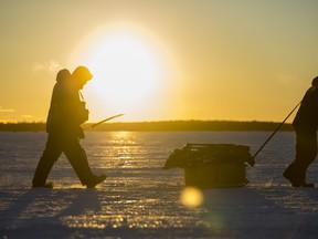 Fishermen carry their gear back to shore as the sun sets after a day of ice fishing on the Bay of Quinte. Sunday near Point Anne, Ontario. ALEX FILIPE