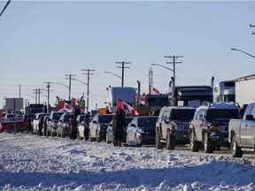 Truckers protesting a COVID-19 vaccine mandate for those crossing the Canada-U.S. border cheer are seen on the Trans-Canada Highway west of Winnipeg earlier this week. DAVID LIPNOWSKI/THE CANADIAN PRESS