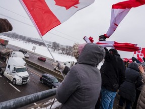 Demonstrators cheer at a convoy of truckers passing Thursday under the Glen Miller Road overpass on Highway 401 in Quinte West. Supporters flocked to overpasses all along the highway in support of the Freedom Convoy, a group of truckers from across the country who are converging on Parliament Hill in opposition to new double-vaccine rules for truck drivers crossing the border. ALEX FILIPE