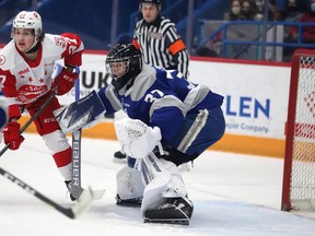 Jonathan Lemaire (32) of the Sudbury Wolves and Justin Cloutier (37) of the Soo Greyhounds keep their eyes on the puck during OHL action at Sudbury Community Arena on Sundaym January 2, 2022. The Greyhounds defeated the Wolves 4-2.