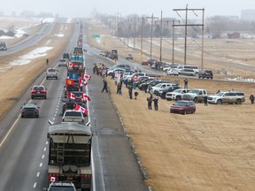 Supporters of the “freedom convoy” of truckers gather on the edge of the Trans-Canada Highway east of Calgary on Monday.