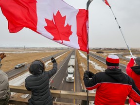 Supporters of the “freedom convoy” of truckers gather on an overpass over the Trans-Canada Highway east of Calgary on Monday, January 24, 2022.