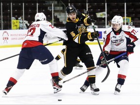 Sarnia Sting's Marko Sikic (15) tries to slip between Windsor Spitfires' James Jodoin (77) and Nicholas DeAngelis in the first period at Progressive Auto Sales Arena in Sarnia, Ont., on Friday, Jan. 14, 2022. Mark Malone/Chatham Daily News/Postmedia Network