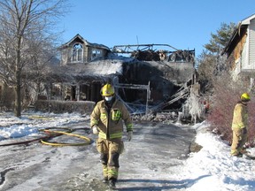 A Kingston Fire and Rescue crew member walks away from a house on Malvern Terrace in Kingston on Monday.