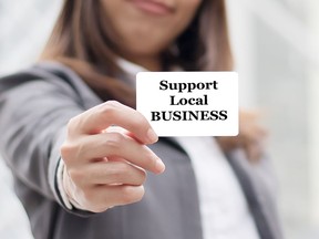 Businesswoman showing card with support local business message