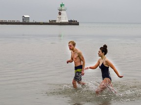 Zane Blaquir of Port Dover and Michelle Lucas of Waterford return to shore after taking a plunge in the frigid waters of Lake Erie at Port Dover on Saturday.