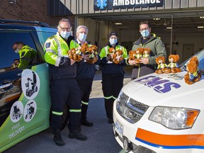 Norfolk County EMS paramedic Steve Weinstein (left), deputy chief Stuart Burnett, paramedic Sam Pacheco hold some of the 500 teddy bears donated by Hauser's Pharmacy and Home Healthcare owner Phil Hauser (right)on Friday.