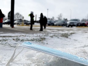 A mask lies discarded in the snow as an intake worker speaks to new arrivals at Brockville's COVID-19 vaccination centre on Monday afternoon. (RONALD ZAJAC/The Recorder and Times)