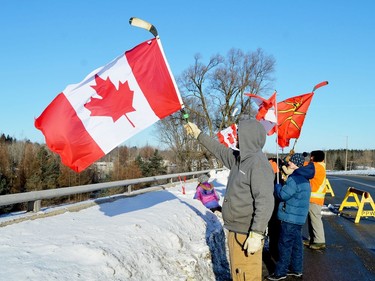 Dozens of people stand on the Edward Street overpass at Highway 401 in Prescott Friday morning to show their support for a convoy of trucks heading to Parliament Hill. (TIM RUHNKE/The Recorder and Times)