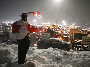 Erin O'Brien of Kingston stands on a snowbank to welcome the trucks taking part in the
Convoy for Freedom 2022 as they arrive in the city on Thursday, Jan. 27, 2022. The convoy is on its way to Ottawa on Friday for a rally on Parliament Hill. Elliot Ferguson/The Kingston Whig-Standard/Postmedia Network