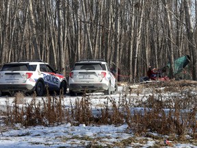 A pair of Kingston Police vehicles park near a tent off the K&P Trail just behind the Integrated Care Hub on Montreal Street on Monday.