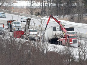 A tow truck removes a truck from the eastbound lanes of Highway 401, approximately one kilometre west of Highway 15 in Kingston on Monday.