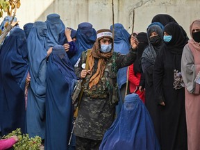 A Taliban fighter, centre, stands guard as women wait in a queue during a World Food Program cash distribution in Kabul on Nov. 29. The United Nations said on Jan. 11 it needed $5 billion in aid for Afghanistan in 2022 to avert a humanitarian catastrophe and offer the ravaged country a future after 40 years of suffering.