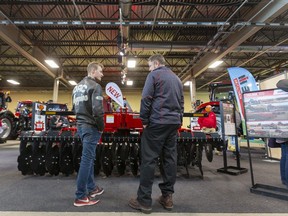 Levi Fretz of Niagara, Ont., talks with Case salesperson Good Mills during the London Farm Show at the Western Fair Agriplex on Wednesday March 4, 2020. (Mike Hensen/The London Free Press)