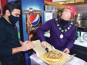 Photo by KEVIN McSHEFFREY/THE STANDARD
Pizza Hut area manager Tirth Patel and Elliot Lake Mayor Dan Marchisella slice up a pizza at the grand opening of the pizza franchise in the city. Marchisella said he has experience in slicing pizza. When he was younger one of his first jobs was making pizza at the former Roadhouse Inn, which was where Shoppers Drug Mart now sits. For the story, see page 7.