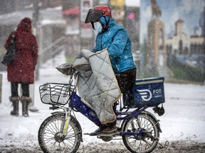 A food delivery person rides along a downtown Toronto street through a blizzard at this time last year. Not everyone has the option of staying home and staying safe.