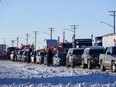 Protesters of COVID-19 restrictions and supporters of Canadian truck drivers protesting the COVID-19 vaccine and all government mandates, cheer on a convoy of trucks on their way to Ottawa, on the Trans-Canada Highway west of Winnipeg, Man., on Tuesday.
