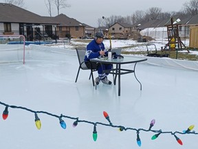 Lambton College professor Justin Randall showed up for a Wednesday virtual class in full hockey gear and with his laptop set up on a patio table on the backyard rink at his home in Corunna.  (PAUL MORDEN, The Observer)