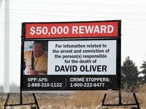 Snow falls in front of a sign offering a $50,000 reward for tips in an unsolved homicide investigation on Friday, Jan.  14, 2022, in Kettle and Stony Point First Nation, Ont.  (Terry Bridge/Sarnia Observer)