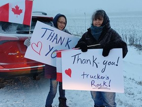 Sam Minielly, left, of Chatham and Sandra Cameron of Wyoming hold signs across from the truck stop in Reece’s Corners Sunday morning in support of a convoy protesting pandemic rules.