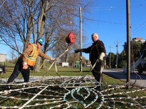 Marc-Andre Brooks, left, a volunteer with the Celebration of Lights, and board member John Charest are shown in this file photo preparing a piece of the candle arch display to be raised into position in November on Front Street in Sarnia.