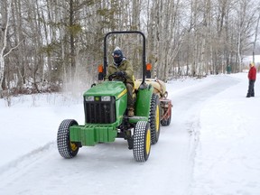 Don Walinga, director of maintenance operations for Cedar Green Golf Course, spreads water for a new skating path at Timberwolf Golf Club, while Jamie Camilucci, Timberwolf's maintenance director, looks on in the background.