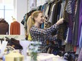 Female Shopper In Thrift Store Looking At Clothes