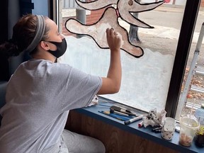 Taylor Larson, one of the youth artists, paints a holiday mural of a character from The Nightmare Before Christmas on the window of Out To Lunch Cafe
Supplied