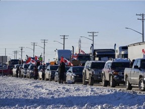 Truckers protesting a COVID-19 vaccine mandate for those crossing the Canada-U.S. border cheer are seen on the Trans-Canada Highway west of Winnipeg earlier this week. DAVID LIPNOWSKI/THE CANADIAN PRESS