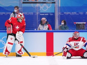 Sudbury Star columnist Randy Pascal, centre, can be seen while  Swiss goelie Leonoardo Genoni and the Czech Republic netminder Patrik Bartosak have a conversation during warm-ups prior to men’s qualification round action at the Beijing 2022 Olympic Winter Games at National Indoor Stadium in Beijing, China on February 15, 2022. Pascal is working at the Games as an off-ice hockey official.