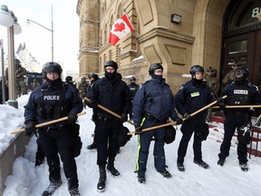 A line of police officers pushes past the offices of the Prime Minister Justin Trudeau as they move to remove protesters on February 19, 2022 in Ottawa. (Photo by DAVE CHAN/AFP via Getty Images)
