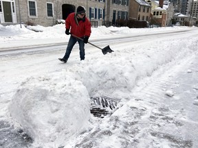 Andrew Landy did his part to clear the municipal sewer grate in front of his home on Earl Street in Kingston, Ont., on Sunday, Feb. 20, 2022. Steph Crosier/The Kingston Whig-Standard/Postmedia Network