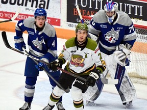 Brandon Coe of the visiting North Bay Battalion takes up position in front of goaltender Mitchell Weeks of the Sudbury Wolves as Jacob Holmes stands guard in Ontario Hockey League action Sunday. Coe returned from a three-game absence.
Sean Ryan Photo