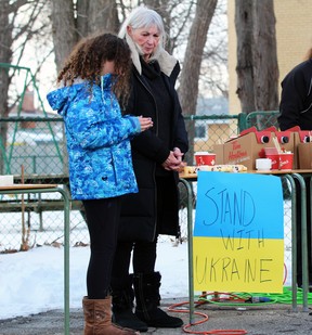 Stephanie Czornyj and granddaughter Kalyna Taylor, 11, stand next to a sign that says, “Stand with Ukraine,” during a vigil for the country amid the Russian invasion at St. George's Ukrainian Catholic church on Sunday, Feb.  27, 2022 in Sarnia, Ont.  Terry Bridge/Sarnia Observer/Postmedia Network