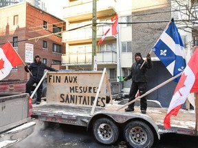 Protesters on a flat-bed truck hold up Canadian and Quebec flags as they demonstrate in the residential downtown area of Ottawa in early February.