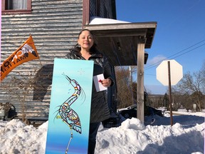 Charmaine Jenner (Tauchkwe), a self-taught Neyaashiinigmiing artist poses with her painting of a crane, a 15-foot reproduction of which will hang on the house behind her in Oxenden as a community-funded symbol of grassroots reconciliation efforts. Photo submitted.