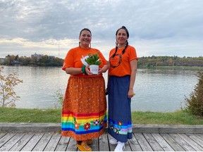 Janine Seymour standing by the water (nibi), with Anishinaabekwe Karen Kejick from Iskatewizaagegan #39, following a traditional water offering ceremony. Women hold sacred roles and responsibilities in our community.
