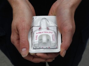 An OPP officer holds a single nasal-spray dose of naloxone.