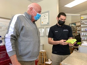 Brian MacPhee picks up a free rapid COVID-19 test on Wednesday from pharmacist Justin Chan at Eagle Place Apothecary on Erie Avenue in Brantford. The province will provide 5.5 million of the tests weekly to be distributed at no charge through participating grocery stores, pharmacies and organizations that serve high-risk communities. Chan said he received three cases and ordered more for next week. The government said the Health Minister Christine Elliott said the tests are meant to support people over the next eight weeks as public health measures are eased in a "cautious and prudent" manner.