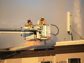Two Cochrane firefighters battle flames appearing from the roof of the local Ramada hotel during a February 6 fire. Patrick Gibson/Cochrane Times