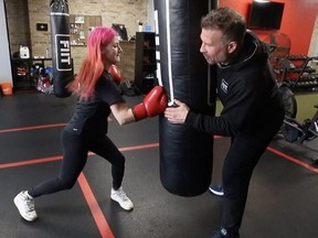 Sophia Logie, 16, works the heavy bag with Jason Battiste, owner of FIIT (Fight Inspired Interval Training) on Gerrard St. at Jones Ave., on Jan. 31, 2022.