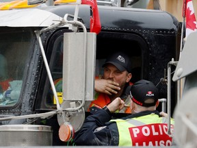 A trucker speaks with an Ottawa police officer as protests against the COVID-19 vaccine mandates continue in Ottawa on Feb. 2.