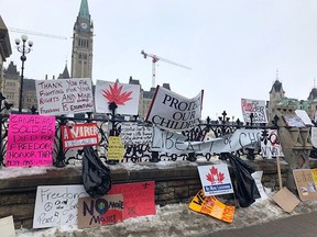 Signs protesting the vaccination mandate for cross-border truckers and in support of the so-called Freedom Convoy line the wrought iron fence along Wellington Street on Parliament Hill in Ottawa on Wednesday.